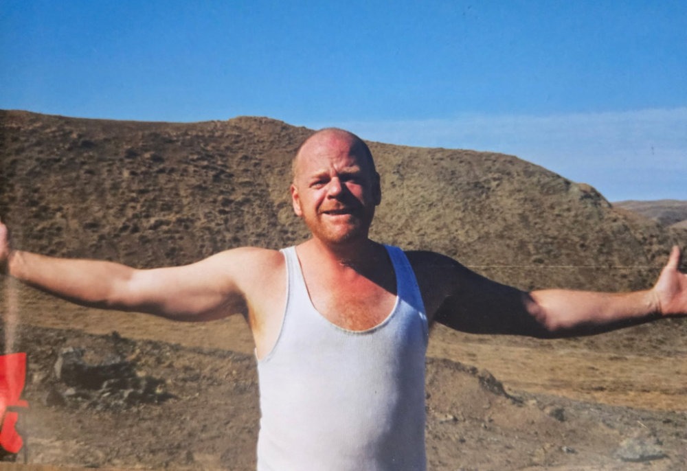 Tom Dryden with arms outstretched in the Alberta Badlands